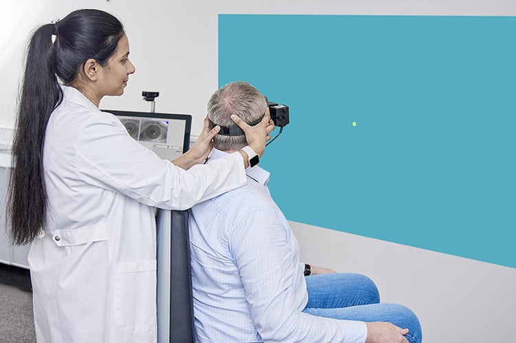 Clinician performing body right SPNT subtest in patient sat in Orion Reclining rotary chair and wearing VisualEyes VNG goggles.
