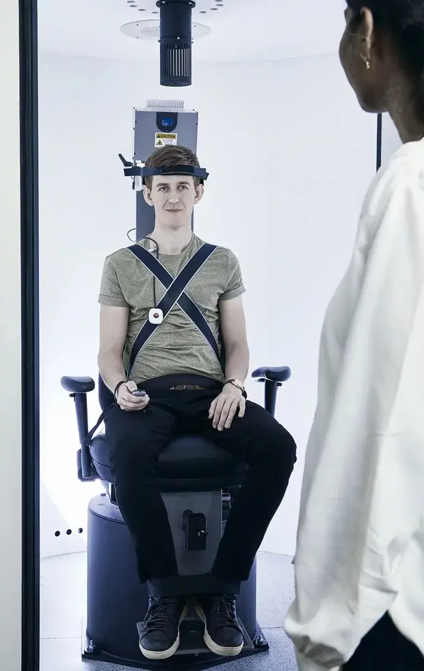 Young man in Orion Auto-Traverse chair looking at female clinician