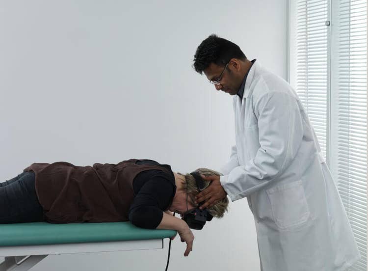 Male clinician rolling female patient onto her stomach with head hanging over the examination bed.