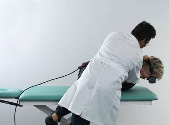 Male clinician holding female patient in a side-lying position, with the patient's head facing toward the floor.