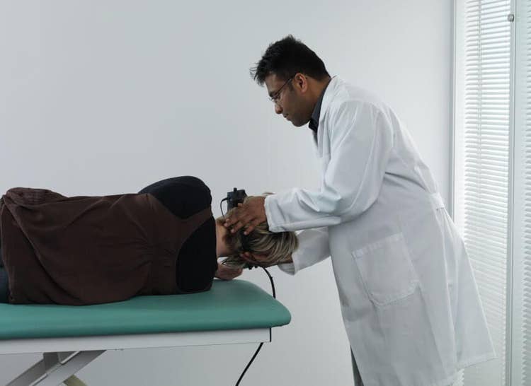 Male clinician rolling female patient onto her right.