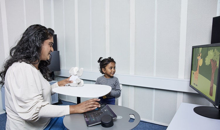 Using the Touch Keyboard, a clinician is performing VRA in an infant, who is looking toward a visual reinforcer to their left.