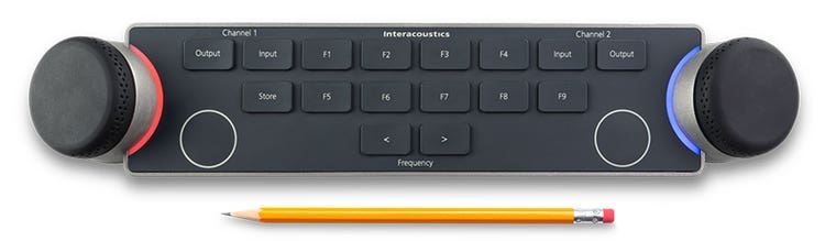 Audiometer Keyboard seen from above with a pencil below. For size comparison, the pencil is approximately two thirds the width of the keyboard. There are two dials located on the left and right sides of the keyboard. The dials are encircled by LED lights which indicate different functions when in use. There are several keys between the multi-functional dials, which include and are not limited to input and output for channels one and two, store, two keys to decrease or increase the intensity, and nine F-keys labeled F1 to F9.