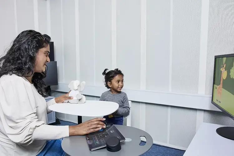 An audiologist in a sound booth with a child performing visual reinforcement audiometry