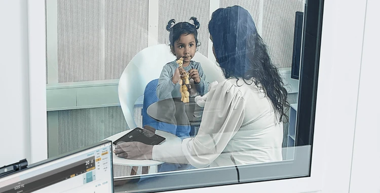 Clinician sat in booth with a young child and operating the Touch Keyboard