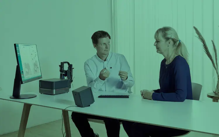 Male clinician showing a hearing aid to his female patient.