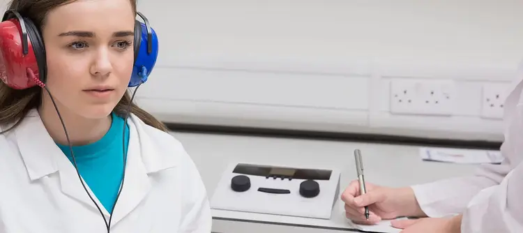 Female clinician performing hearing screening in young woman