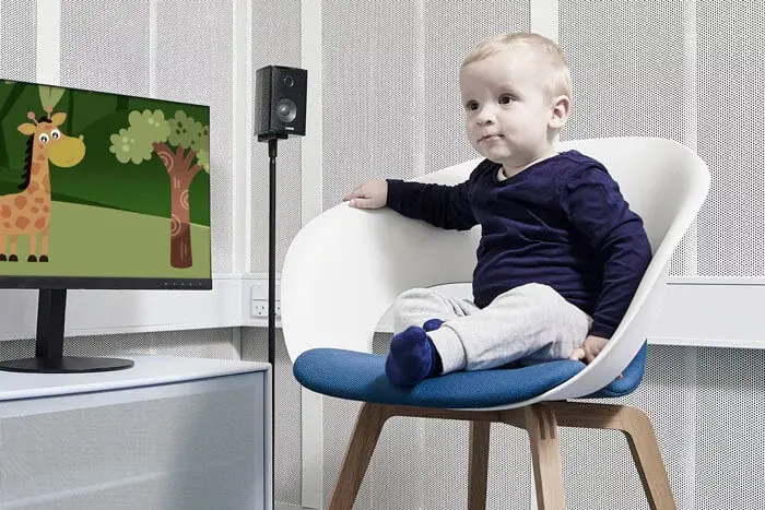 toddler sitting in chair next to computer screen with animated giraffe