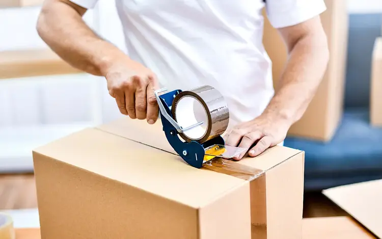 Employee sealing a cardboard shipping box with packing tape