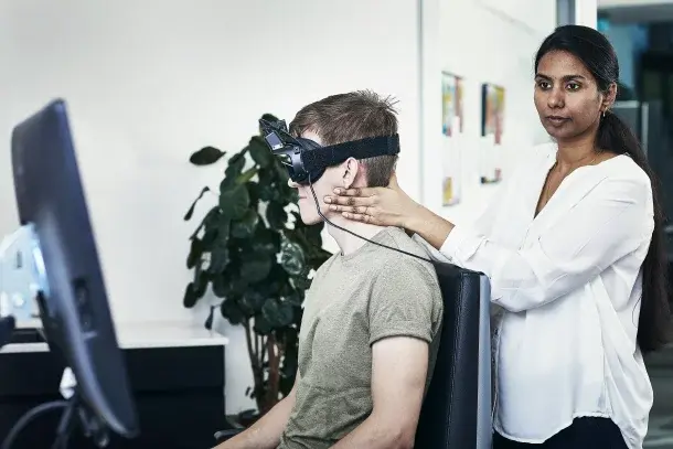A clinician fits video goggles on a patient for vestibular testing