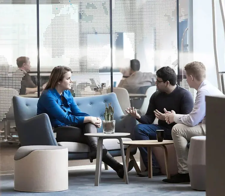 Employees in conversation over coffee in a bright office lounge