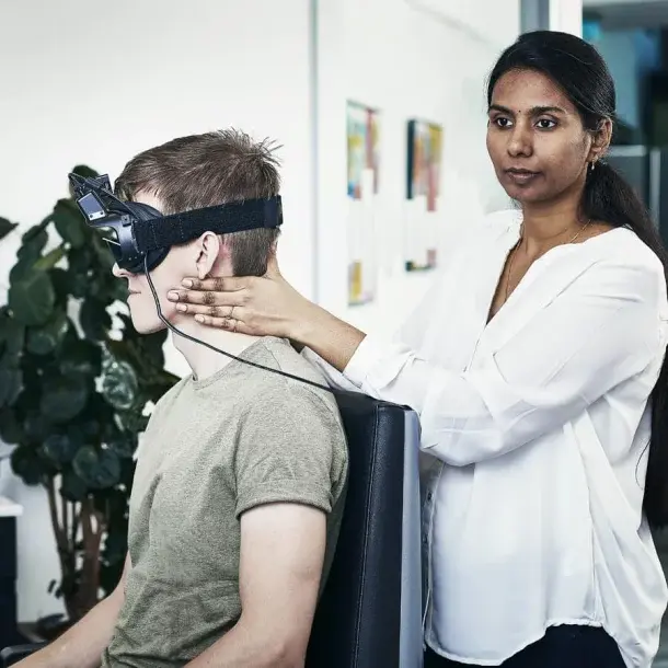 Clinician performing a balance test on a patient wearing video goggles
