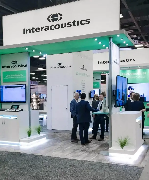 Visitors talking at the Interacoustics booth at an audiology tradeshow