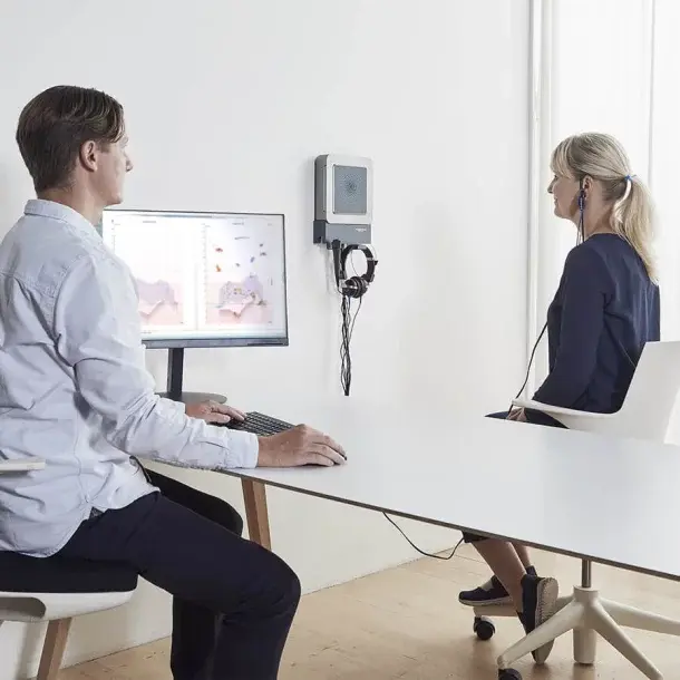Hearing aid fitting session with a clinician and client reviewing results on screen