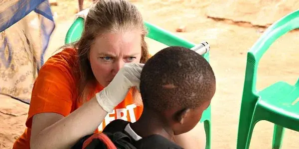 Volunteer examining a child's ear during a hearing screening in Malawi